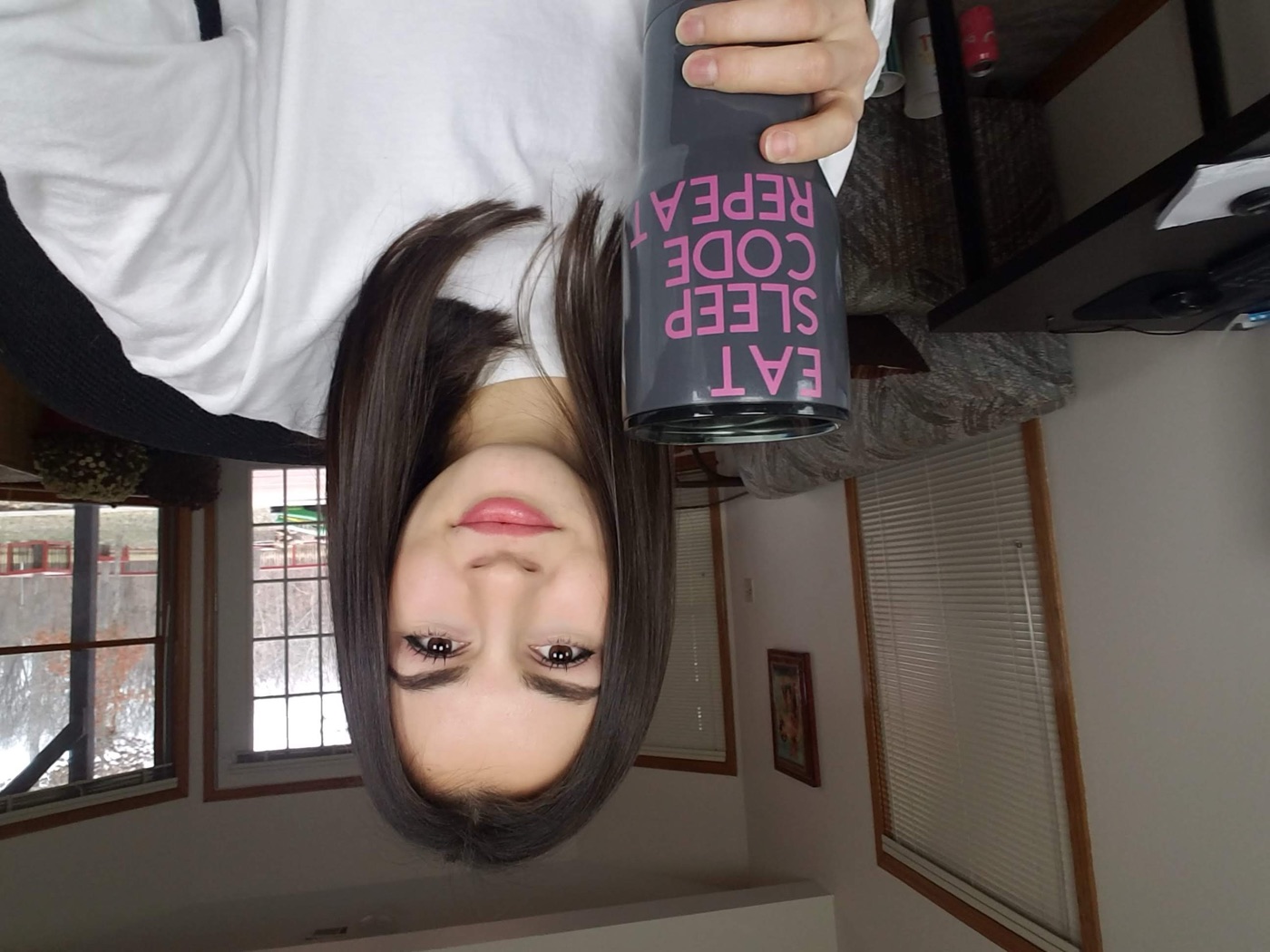 Lilly holding a mug that reads Eat Sleep Code Repeat